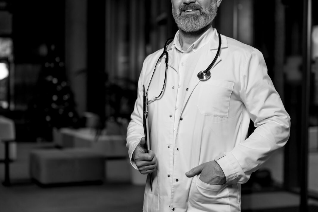 Mature male doctor in lab coat entering the clinic and looking determined